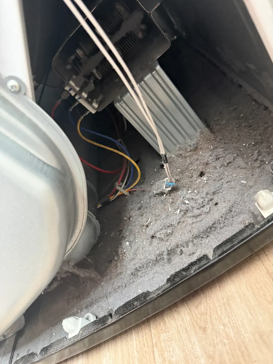 Lint buildup inside an electric dryer cabinet before cleaning