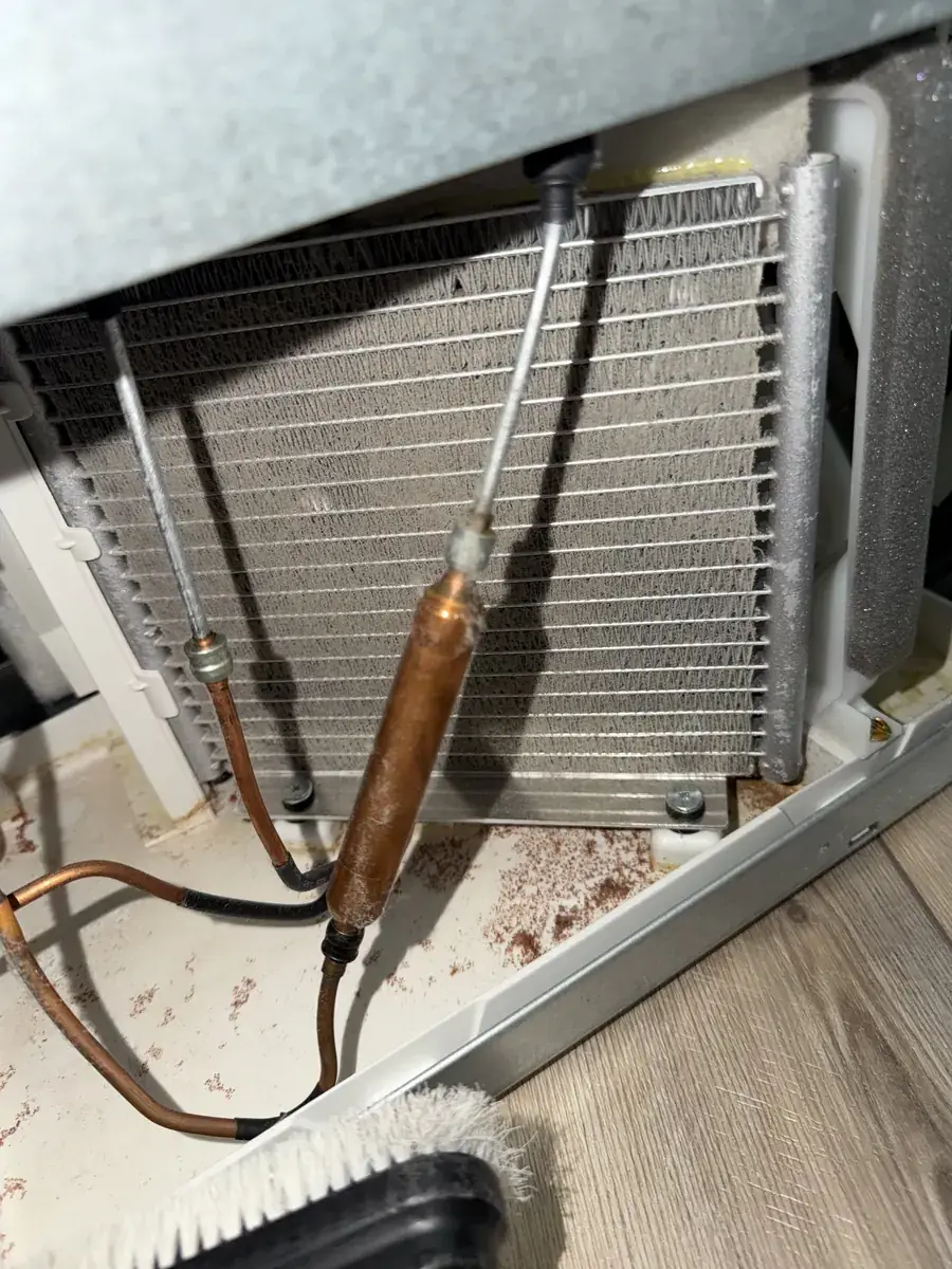 Dust and debris across a refrigerator condenser airflow area during inspection