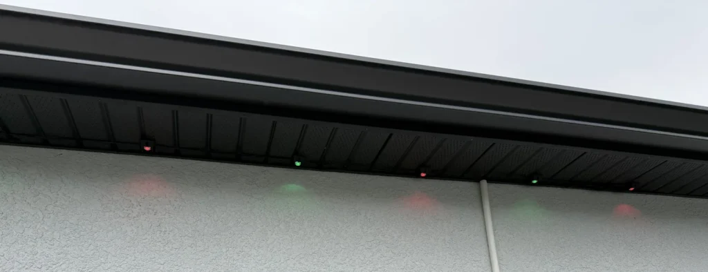 Close view of permanent outdoor lights installed beneath a dark soffit