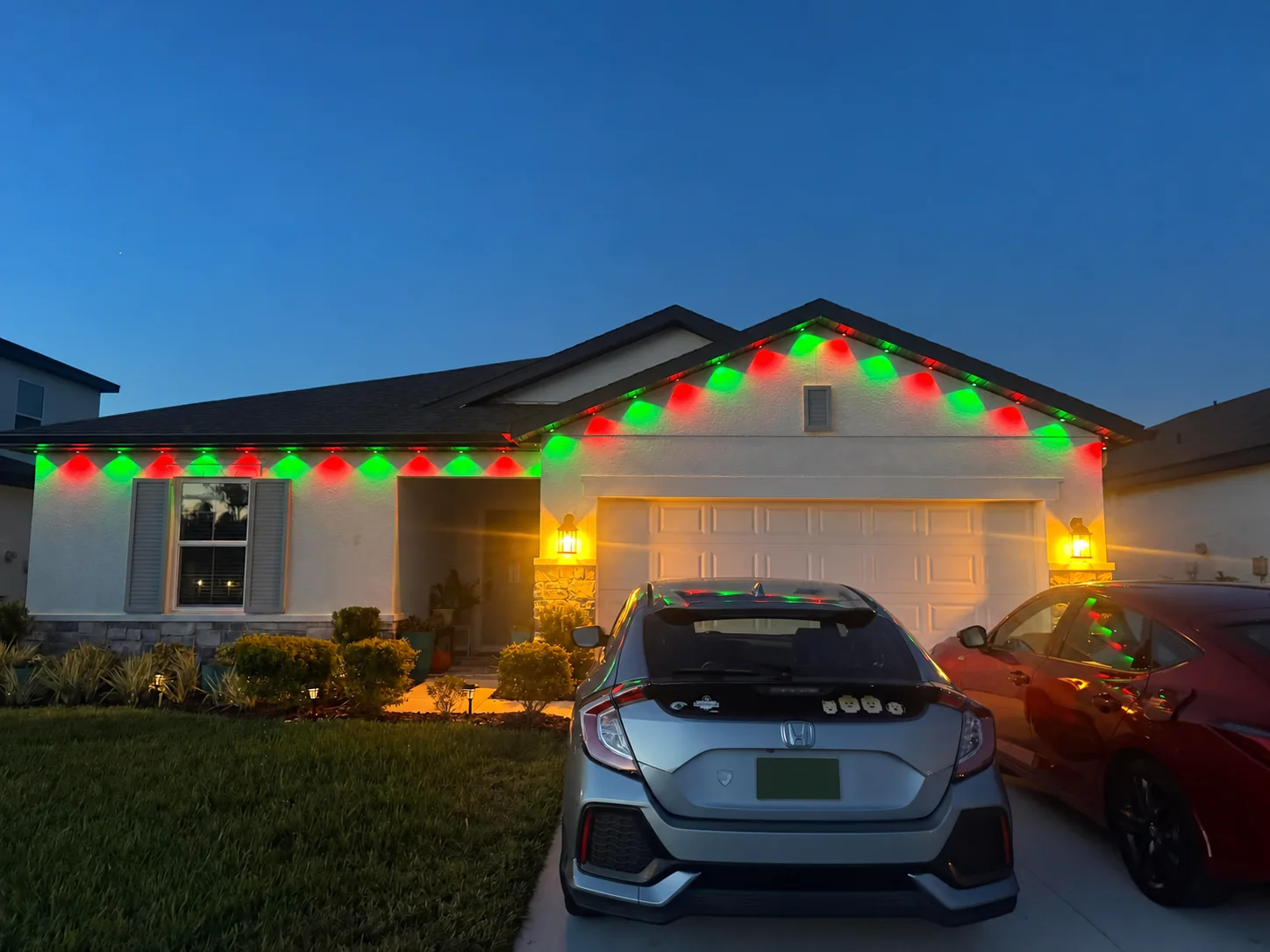 Completed permanent outdoor lighting displaying red and green Christmas colors